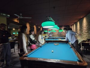 Menschen stehen bei einem Billardtisch in einem Restaurant und spielen Billard.