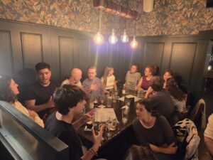eine Gruppe von Menschen sitzen in einem Pub und plauedern.