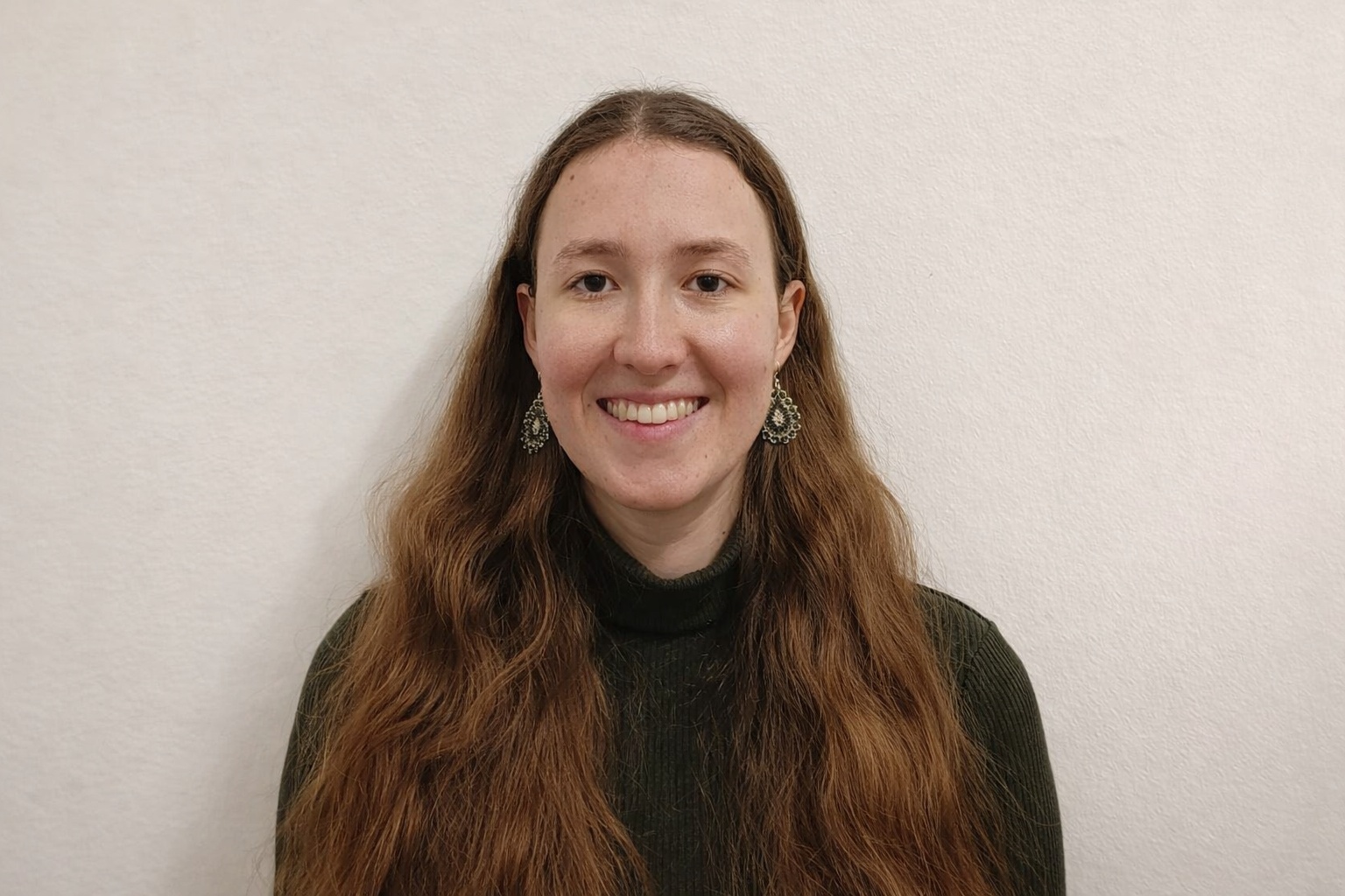 Eine lächelnde Junge Frau vor einer weißen Wand